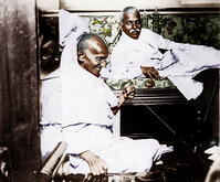 Mahatma Gandhi spinning in the cabin of Pundit Madan Mohan Malaviya (right) on board of S.S. Rajputana during his voyage to England, Bombay, August 1931. [AKG110392629]