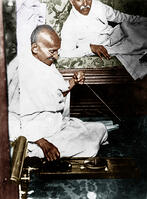 Mahatma Gandhi spinning in the cabin of Pundit Madan Mohan Malaviya (right) on board of S.S. Rajputana during his voyage to England, Bombay, August 1931. [AKG110392630]