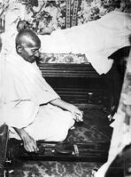 Mahatma Gandhi spinning in the cabin of Pundit Madan Mohan Malaviya (seen in background) on board of S.S. Rajputana during his voyage to England, Bombay, August 1931. [AKG110392631]