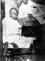 Mahatma Gandhi spinning in the cabin of Pundit Madan Mohan Malaviya (right) on board of S.S. Rajputana during his voyage to England, Bombay, August 1931. [AKG110392633]