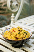 Food, Cooked, Pasta, Bowl of Moroccan couscous with fruit nuts and vegetables on a metal table in a garden. [PST110004318]