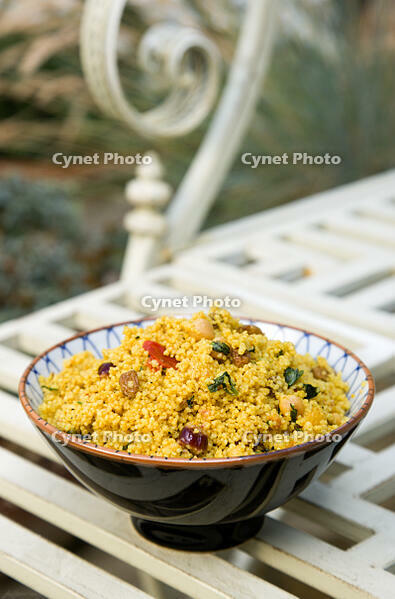 Food, Cooked, Pasta, Bowl of Moroccan couscous with fruit nuts and vegetables on a metal table in a garden. [PST110004318]
