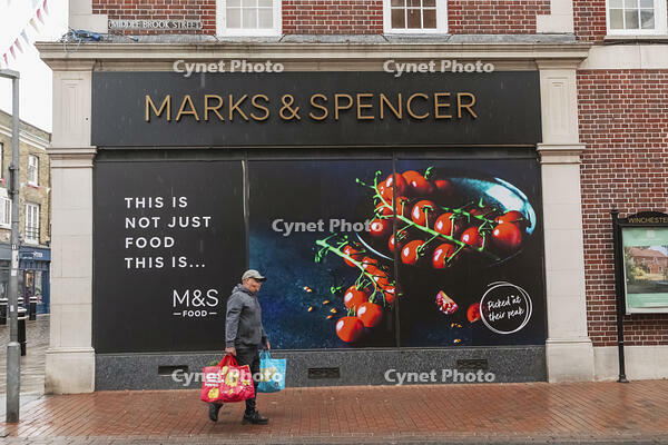 England, Hampshire, Winchester, The High Street, Street Scene with Person passing by Shop Window Advertising [STV110084007]