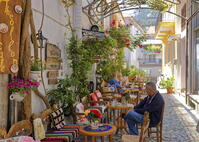 Greece, Lesvos, Agiassos. People sitting in a colourful alleyway beside Theofilon Cafe. [AWL110001939]