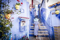 Rear view of woman looking at beauty potted plants hanging out traditional blue houses, Chefchaouen, Morocco [AWL110001957]