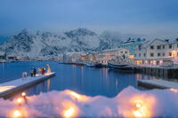Tourists on a jetty covered with snow admiring the village of Henningsvaer, Lofoten islands, Norway [AWL110002045]