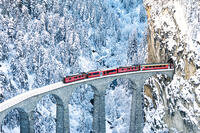 Train on Landwasser viaduct entering in a tunnel carved into a mountain ridge in winter, Filisur, Graubunden canton, Switzerland [AWL110002252]