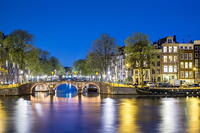 Netherlands, North Holland, Amsterdam. Canal houses along the Amstel River at night. [AWL110002465]