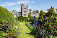 Kendal, Cumbria, England.  Roses and delphiniums frame a view of Levens Hall and its Pele Tower. [AWL110002555]