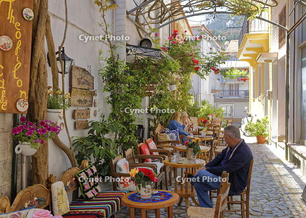 Greece, Lesvos, Agiassos. People sitting in a colourful alleyway beside Theofilon Cafe. [AWL110001939]