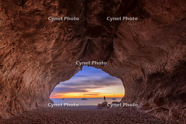 Lonely person looks colors of the sunrise inside the sea cave on the beach of Cala Luna, Baunei, Ogliastra province,  Sardinia, Italy (MR) [AWL110002084]