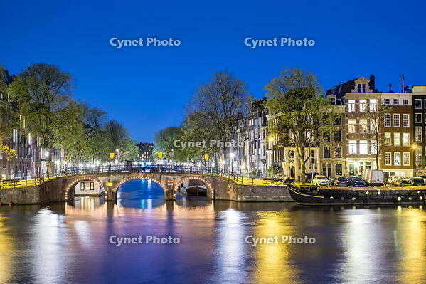 Netherlands, North Holland, Amsterdam. Canal houses along the Amstel River at night. [AWL110002465]
