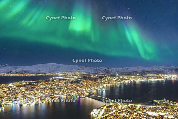 Glowing Northern Lights in the night sky over Tromso city and fjord, Norway [AWL110002474]