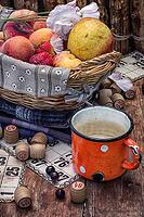 Composition of the enamel cup with water on the background fruit basket and Lotto games for picnic [IBR122665454]