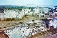British expatriate tourist woman sitting on bench by walls ruin thought to be Malacca or Melaka, Malaya, Malaysia, south east Asia c 1964 [IBR112672598]