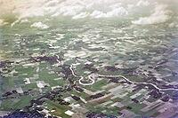 Captioned as 'aerial photo Saigon', meandering river in flat agricultural landscape of paddy fields, Vietnam, south east Asia c 1964 [IBR112672601]