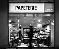 Black and white photograph, Dussmann GmbH, bookshop, urban scene in the evening with reflections in the window pane and a view of the displays and shelves, Berlin, Germany [IBR112672618]