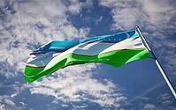 Beautiful national state flag of Uzbekistan fluttering at sky background. Low angle close-up Uzbekistan flag 3D artwork [IBR123569264]
