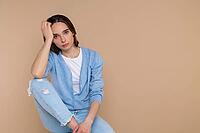 Tired woman in casual clothing leaning head on hand copy space for promotion isolated over beige background [IBR123569300]