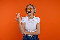 Laughing woman in white t shirt and jeans showing five fingers number isolated over orange background [IBR123569309]