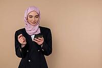 Messaging. Young woman in black suit with a phone in hands [IBR123569312]