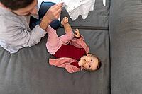 Father with toddler daughter at home, taking care of his baby changing clothes [IBR123569315]