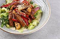 Food, Beef steak salad with cherry tomatoes, cucumbers, red onions, romaine salad and lime mustard olive oil salad dressing on dark background, top view [IBR123622464]