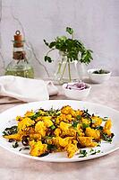 Baked small cauliflower steaks with onions and herbs on a plate on the table vertical view [IBR123629692]