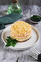Classic mimosa salad with canned fish and vegetables on a plate on the table vertical view [IBR123629719]