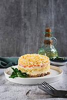 Traditional layered salad with canned fish on a plate on the table vertical view [IBR123629720]