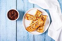 Appetizing croutons in powdered sugar on a plate on the table top view [IBR123629724]
