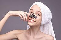 Young caucasian female skincare routine with facial mask and white towel on head smiling [IBR123629751]