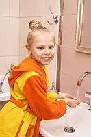 Caucasian female child in colorful bathrobe washing hands in bathroom smiling [IBR123629768]