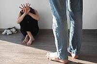 Child girl 7-8 years old sits on floor scared, covering her face with her hands, stands angry man whose face is not visible, father or stepfather, concept of violence, punishment of children [IBR123638378]
