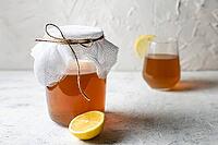 Raw fermented homemade alcoholic or non alcogolic kombucha superfood. Ice tea with healthy natural probiotic in glass with lemon slice on white background [IBR123639493]