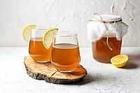 Raw fermented homemade alcoholic or non alcogolic kombucha superfood. Ice tea with healthy natural probiotic in glass with lemon slice on white background [IBR123639497]