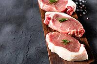 A pieces of raw fresh pork with rosemary on a cutting board on dark background. Meat with spices for recipes and cooking [IBR123639508]