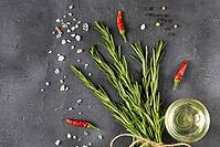 Bunch of green fresh rosemary with pepper, salt, lemon and oil on the dark stone background. Herbs and spices for recipes. Top view with copy space [IBR123639512]