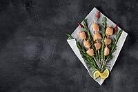 Raw chicken kebabs and rosemary in the form of a bouquet on a dark background. Food background, cooking ingredients. Top view with copy space [IBR123639515]