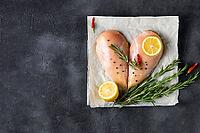 Raw chicken fillet in the shape of a heart with rosemary and spices on dark concrete background. Top view with copy space [IBR123639519]