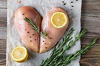 Raw chicken fillet in the shape of a heart with rosemary and spices on natural wooden background. Top view [IBR123639521]