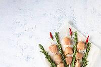 Raw chicken kebabs and rosemary in the form of a bouquet on a light background. Food background, cooking ingredients. Top view with copy space [IBR123639524]