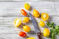 Various colorful ripe tomato on white wooden background. Cooking from yellow orange and red cherry tomatoes. Top view with copyspace [IBR123639564]