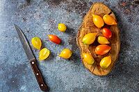 Various colorful ripe tomato on rustic blue background. Cooking from yellow orange and red cherry tomatoes. Top view [IBR123639568]