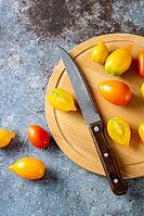 Various colorful ripe tomato on rustic blue background. Cooking from yellow orange and red cherry tomatoes. Top view [IBR123639571]
