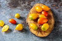 Various colorful ripe tomato on rustic blue background. Cooking from yellow orange and red cherry tomatoes. Top view [IBR123639572]