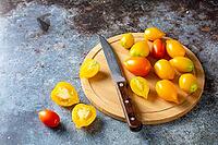 Various colorful ripe tomato on rustic blue background. Cooking from yellow orange and red cherry tomatoes. Top view [IBR123639573]