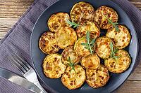 Fried slices of zucchini with sour cream sauce on plate. Fried courgettes with herb for dinner on on natural brown wooden background. Top wiev [IBR123639584]
