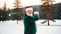 A jolly elderly man dressed as Santa Claus swings a golf club on a snowy course surrounded by pine trees. He wears a green sweater and a festive hat, smiling widely in the winter scenery. AI generated [IBR123641847]