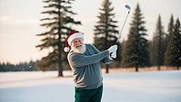 Santa swings his golf club on a snowy course at Christmas, wearing a red hat and cozy casual everyday clothes. Pine trees stand tall in the background, creating a festive winter setting. AI generated [IBR123641849]